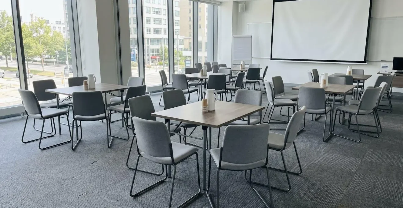 Vue grand angle d'une salle de séminaire moderne vide avec grandes baies vitrées, chaises disposées en cercle, lumière naturelle abondante